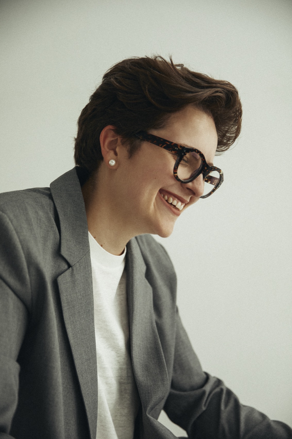 Susana Carrillo con chaqueta gris, sonriendo mientras escucha